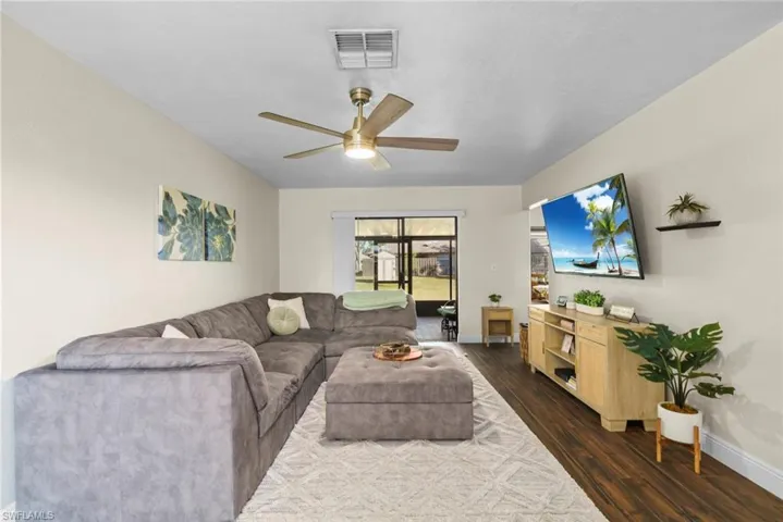 Living room with ceiling fan and dark hardwood / wood-style flooring