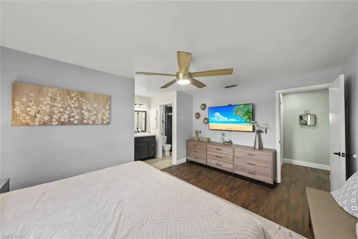 Bedroom featuring dark wood-type flooring, ensuite bath, and ceiling fan