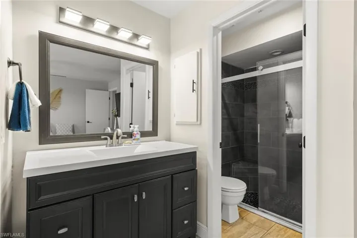 Bathroom featuring vanity, toilet, a shower with shower door, and hardwood / wood-style floors