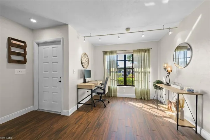 Office space with dark wood-type flooring and track lighting