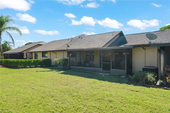 Rear view of property featuring a lawn and a sunroom