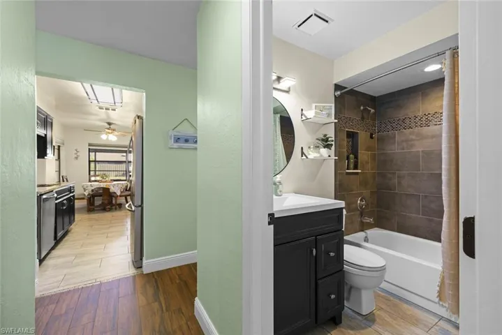 Full bathroom with hardwood / wood-style flooring, ceiling fan, vanity, tiled shower / bath, and toilet