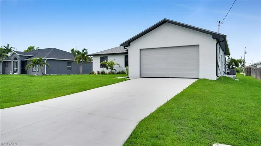 Ranch-style house featuring a garage, a front yard, stucco siding, and concrete driveway