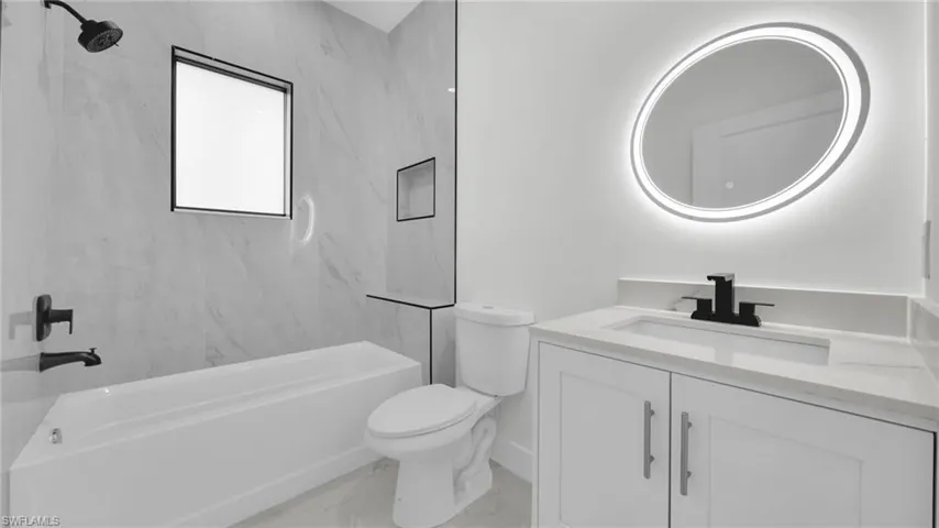 Bathroom featuring vanity, shower / bathtub combination, and light marble finish floors