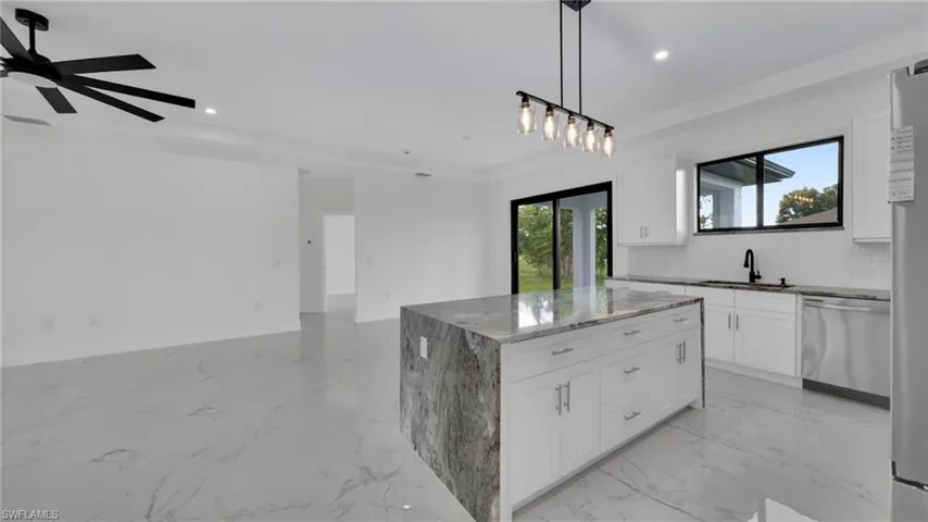Kitchen with a kitchen island, hanging light fixtures, white cabinets, stainless steel appliances, and recessed lighting