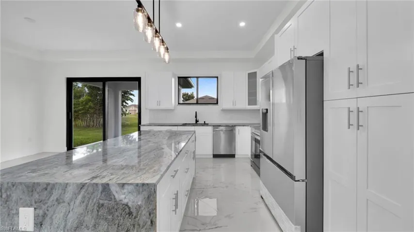 Kitchen with light marble finish floors, appliances with stainless steel finishes, light stone countertops, decorative light fixtures, and backsplash