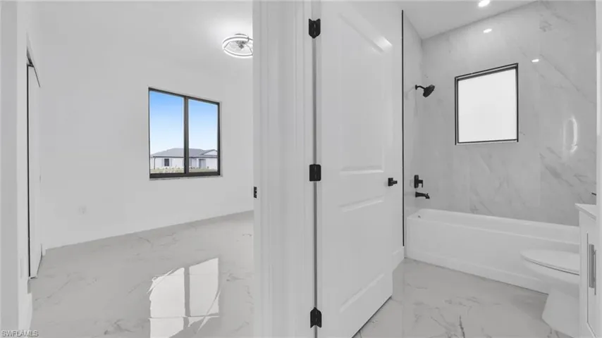 Full bath featuring light marble finish floors, healthy amount of natural light, tub / shower combination, and vanity