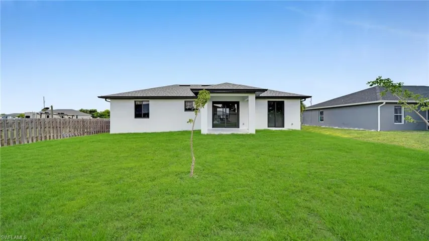 Rear view of house featuring a yard and stucco siding