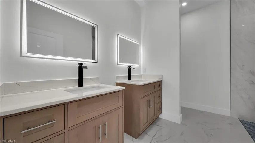Full bathroom featuring light marble finish floors and two vanities