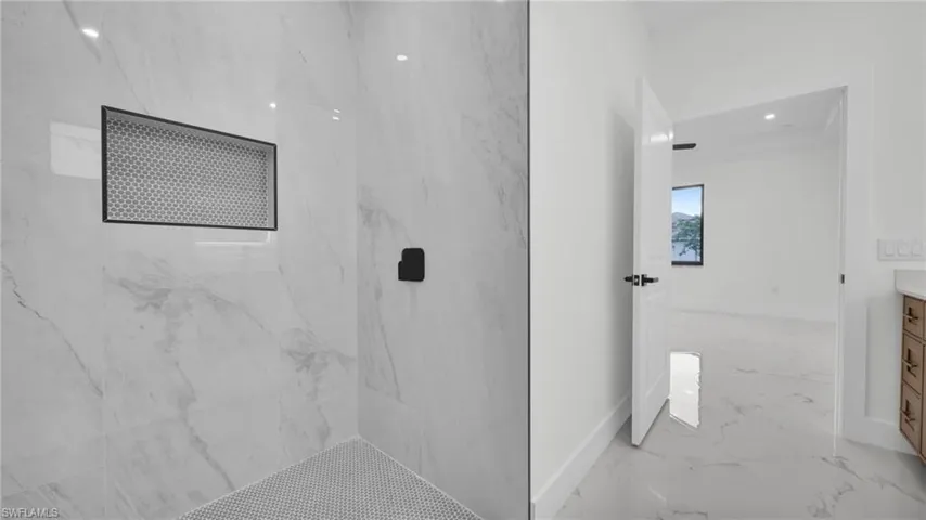 Bathroom with vanity, a marble finish shower, light marble finish flooring, and recessed lighting