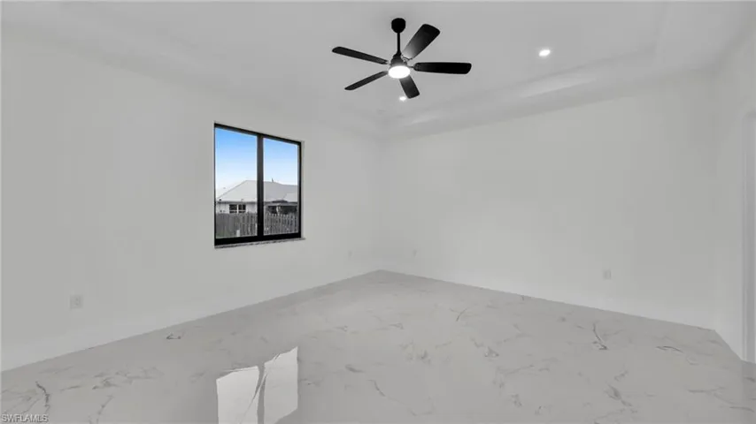 Spare room featuring a tray ceiling, recessed lighting, light marble finish floors, and ceiling fan