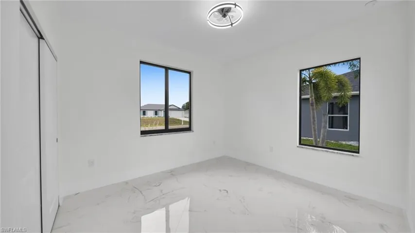 Unfurnished bedroom featuring marble look tile flooring, multiple windows, and a closet