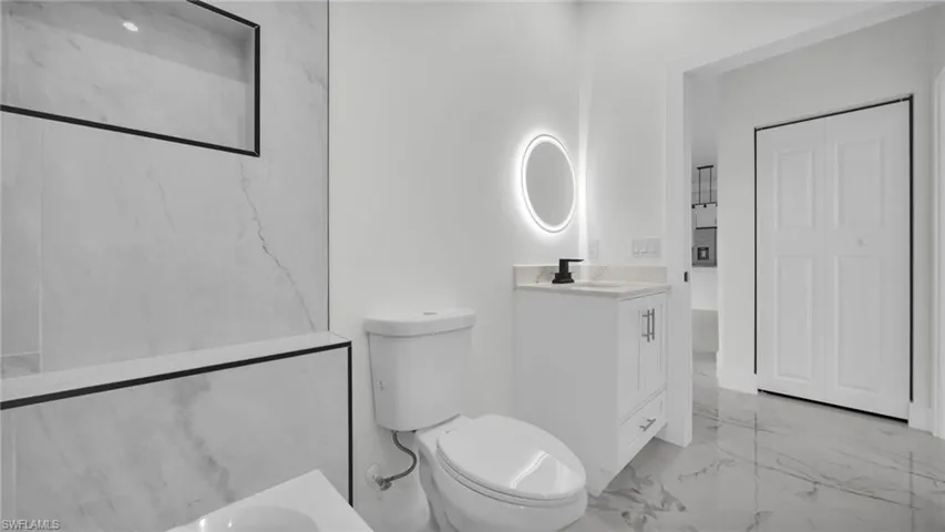 Full bath with vanity, light marble finish flooring, and a closet