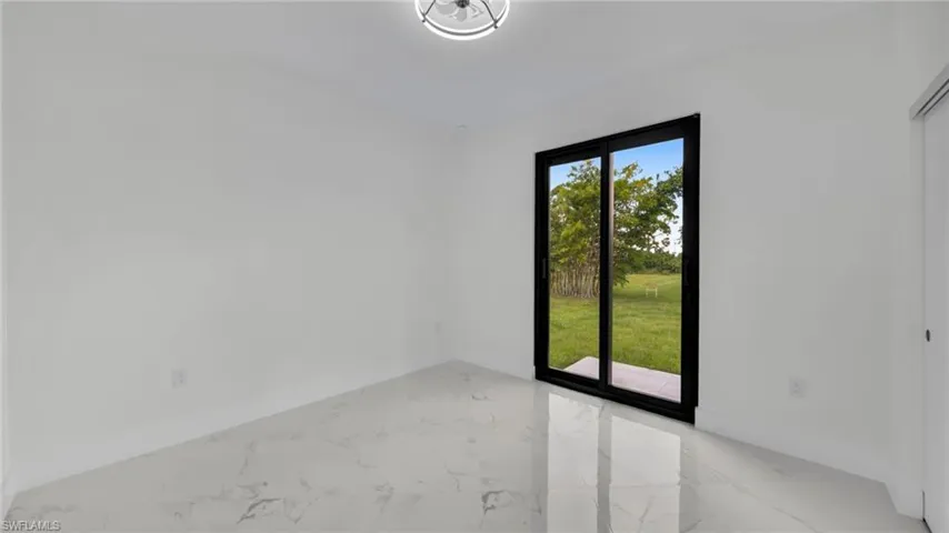 Spare room featuring light marble finish floors and baseboards