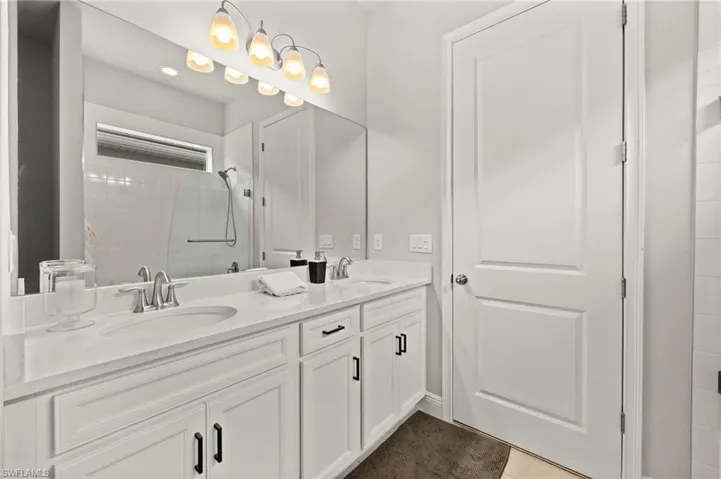 Full bathroom featuring double vanity, a shower stall, and light tile patterned floors