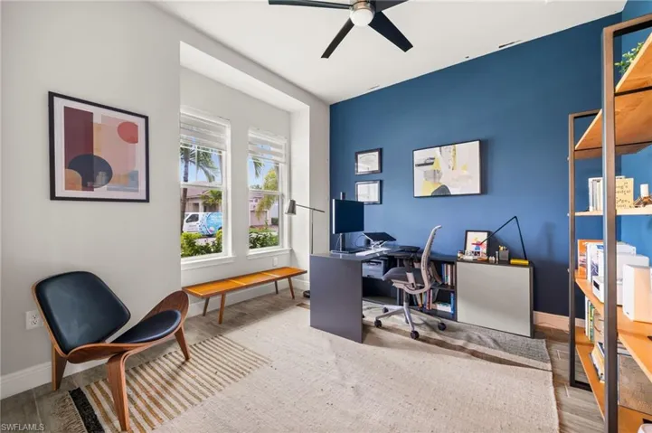 Well-lit interior space featuring wood-finish flooring, a contemporary ceiling fan, and a prominent accent wall