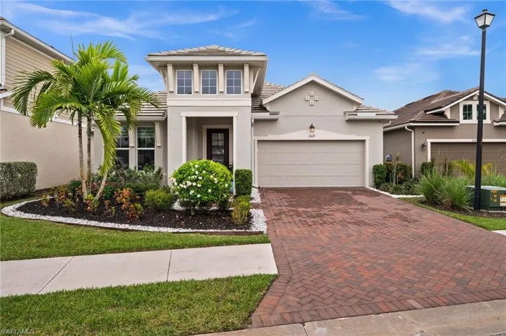 View of front of home with decorative driveway, stucco siding, and an attached garage