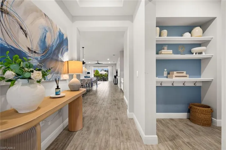 Entryway featuring wood-finish flooring, a built-in shelving unit with a blue accent wall, recessed lighting, and white baseboards