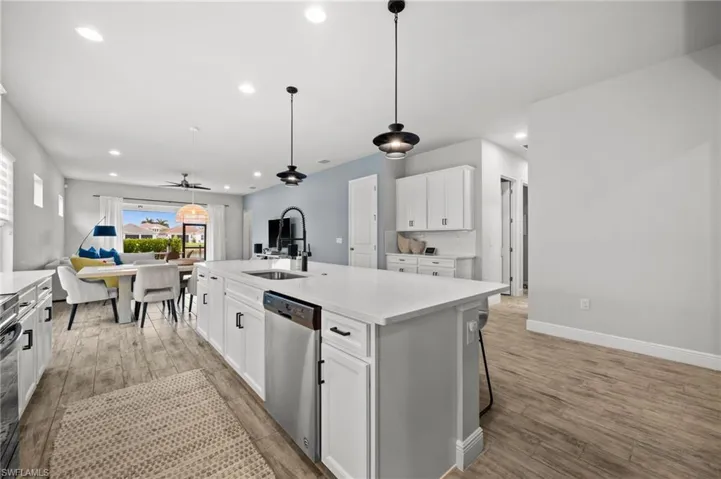 Kitchen featuring white cabinetry, a center island with sink, and pendant lighting