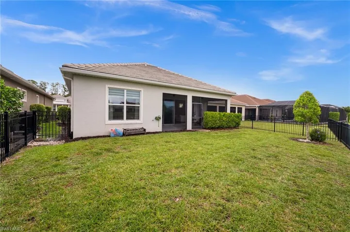 Rear view of property, a fenced backyard, stucco siding, and a tile roof