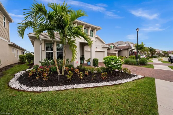 View of front facade featuring stucco siding, decorative driveway, a front lawn, and a residential view