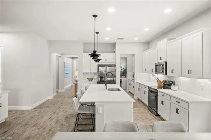 Kitchen featuring white cabinets, a breakfast bar, stainless steel appliances, and tasteful backsplash