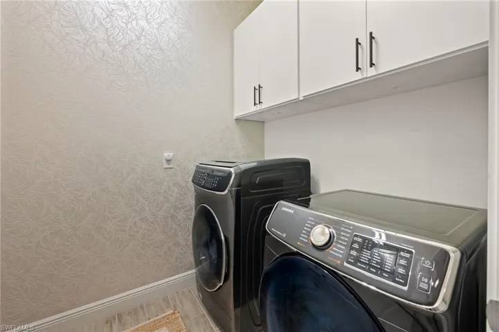 Laundry area with cabinet space, wallpapered walls, and washer and dryer