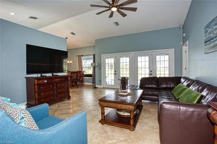 Living room featuring light tile patterned floors, a ceiling fan, and french doors