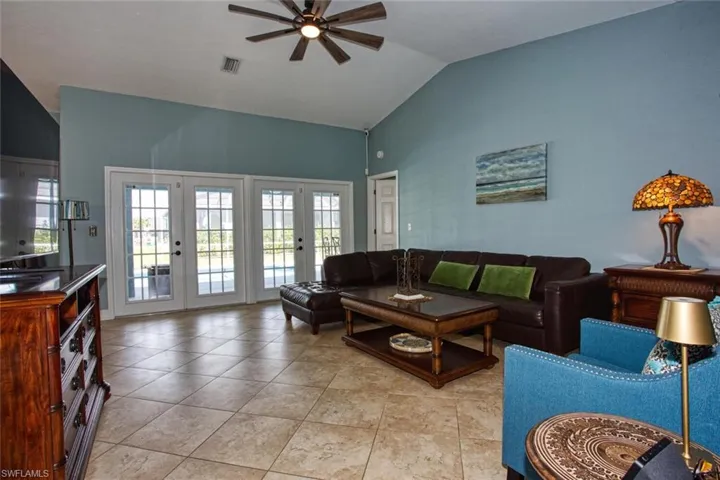 Living area featuring vaulted ceiling, ceiling fan, french doors, and light tile patterned flooring
