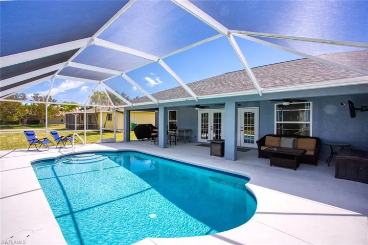 Outdoor pool with a sunroom, a lanai, a patio area, outdoor seating, and french doors