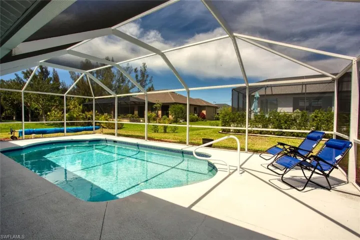 Swimming pool with a sunroom, a lanai, a lawn, and a patio area