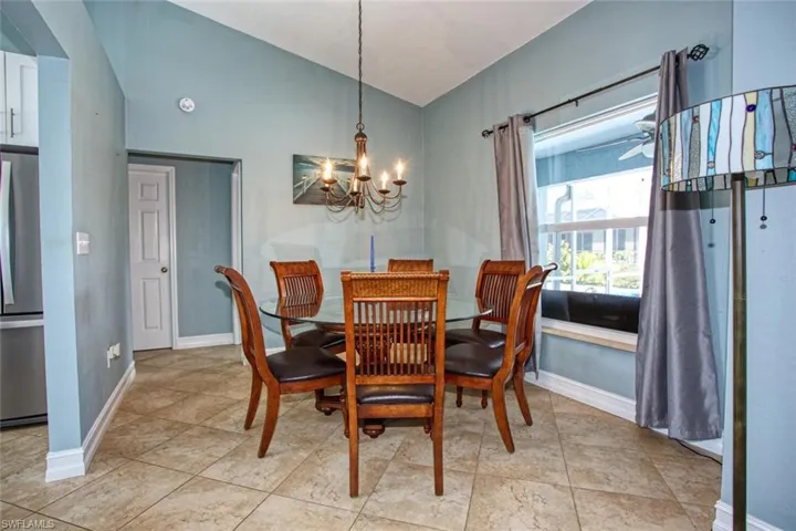 Dining space with vaulted ceiling, suspended lighting, a ceiling fan, and light tile patterned floors