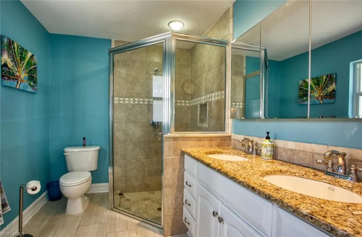 Full bath featuring double vanity and a stall shower