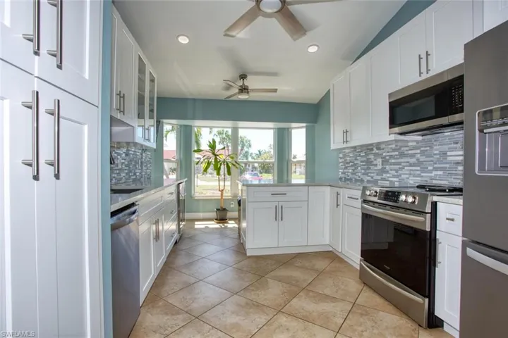 Kitchen featuring white cabinetry, a peninsula, stainless steel appliances, glass insert cabinets, and recessed lighting