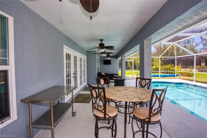 View of patio with french doors, a sunroom, an outdoor pool, a lanai, and a ceiling fan