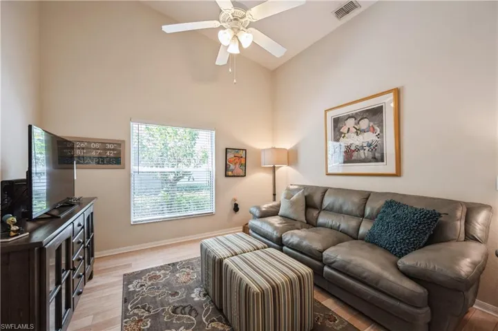 Living room featuring light wood-type flooring, visible vents, ceiling fan, and baseboards