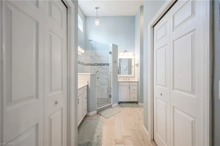 Bathroom featuring wood finished floors, vanity, a closet, and a marble finish shower