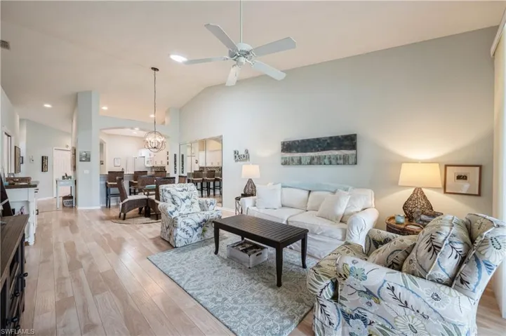 Living area with recessed lighting, arched walkways, light wood-style floors, a ceiling fan, and lofted ceiling