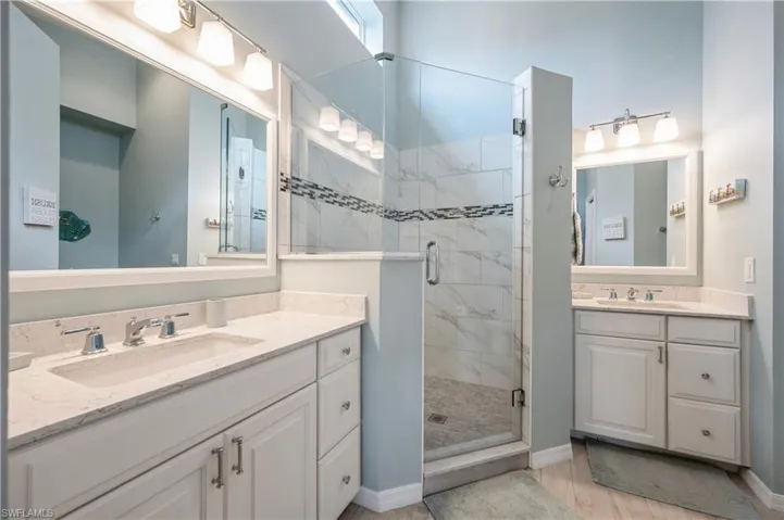 Full bath featuring a stall shower, a sink, and baseboards