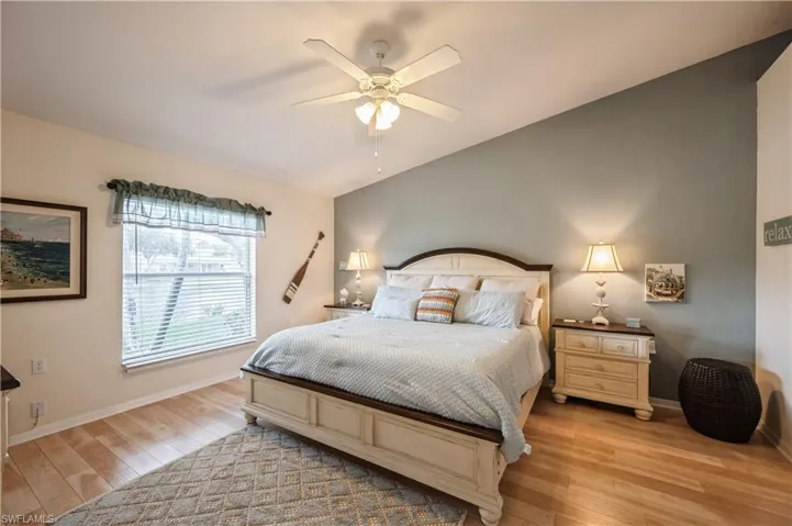 Bedroom featuring ceiling fan, light wood-style flooring, vaulted ceiling, and baseboards