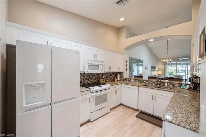 Kitchen featuring tasteful backsplash, arched walkways, white appliances, a sink, and visible vents