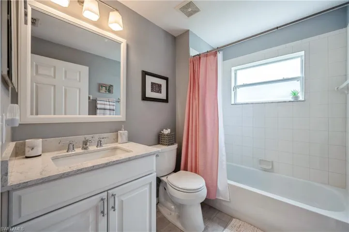Bathroom with shower / bath combo, visible vents, toilet, and vanity