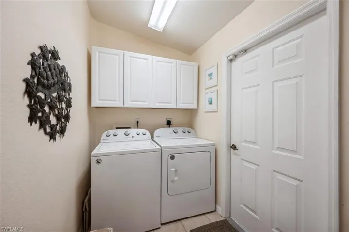Washroom with light tile patterned flooring, cabinet space, and washing machine and dryer