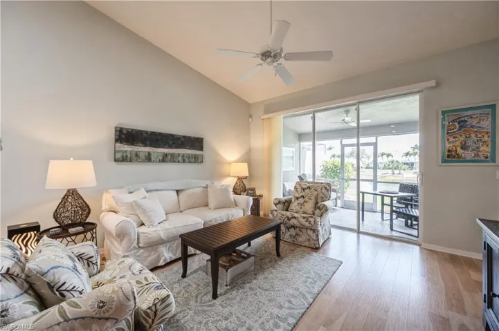 Living room with light wood-style flooring, ceiling fan, vaulted ceiling, and baseboards