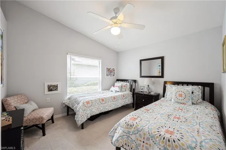 Carpeted bedroom with baseboards, ceiling fan, and vaulted ceiling