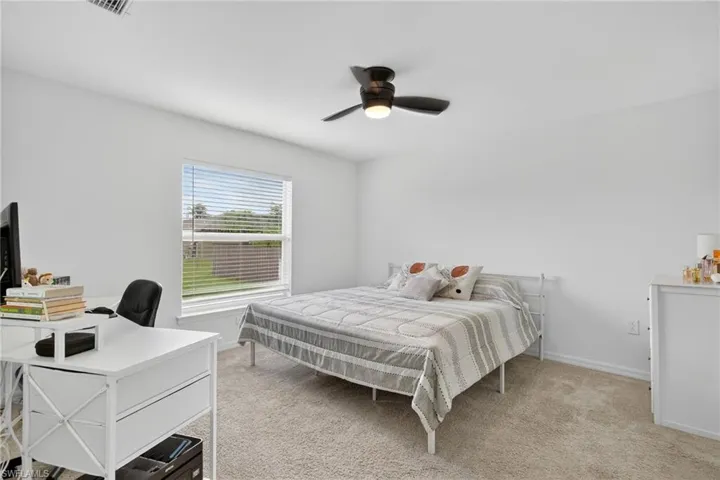 Bedroom with light colored carpet, a desk, and ceiling fan