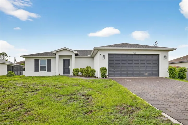 View of front of home featuring stucco siding, a garage, decorative driveway, and a front lawn