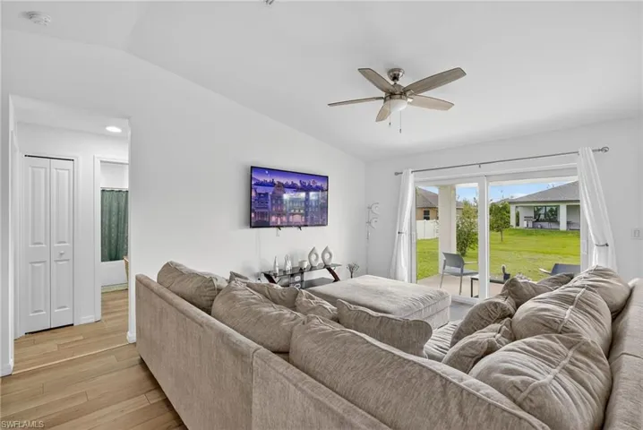 Living area featuring lofted ceiling, light wood finished floors, a ceiling fan, and recessed lighting