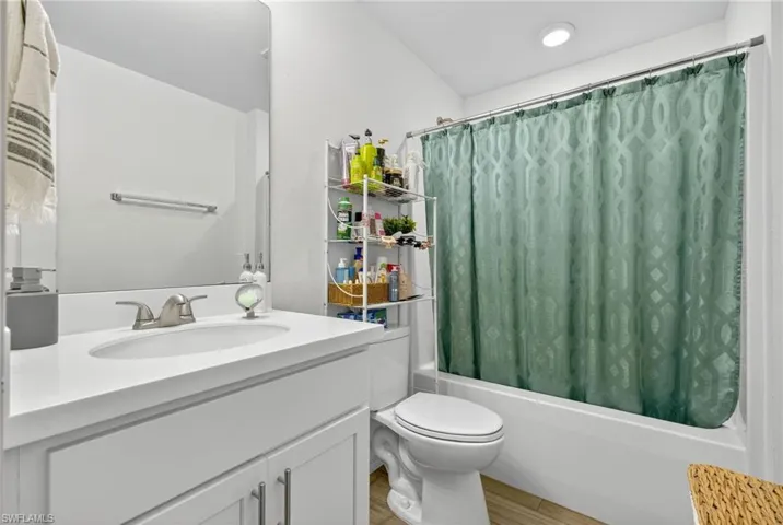 Full bathroom featuring vanity, shower / bathtub combination with curtain, and wood finished floors