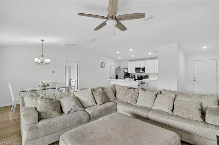 Living area with a chandelier, light wood-style flooring, a ceiling fan, recessed lighting, and lofted ceiling